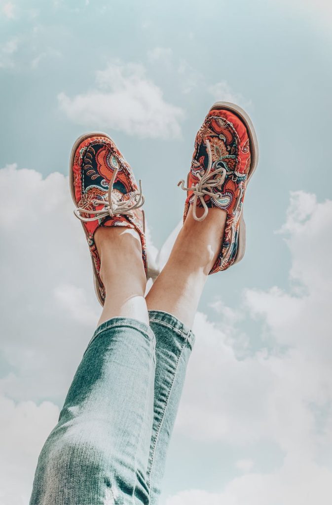 woman lying with legs up against blue sky