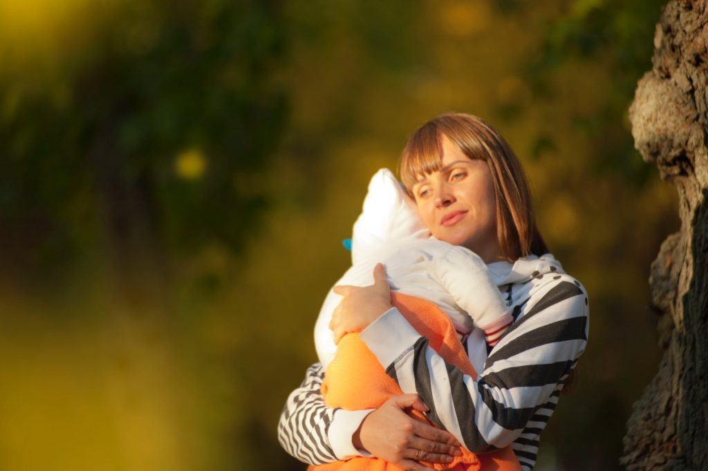 shallow focus photo of woman carrying her baby