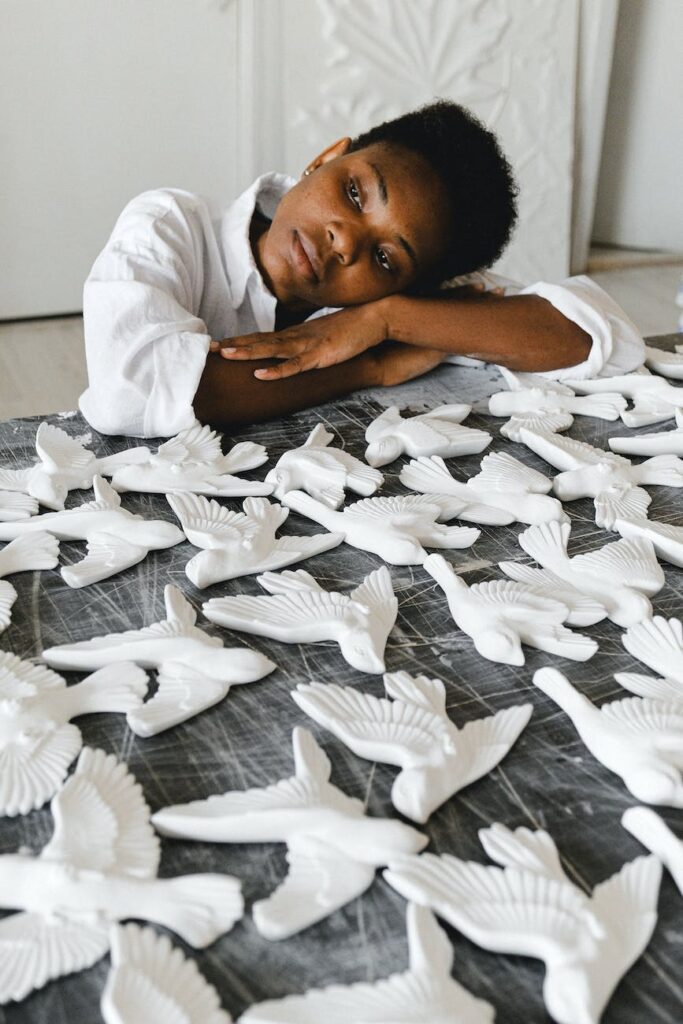 photo of person leaning on the table with ceramic figurines