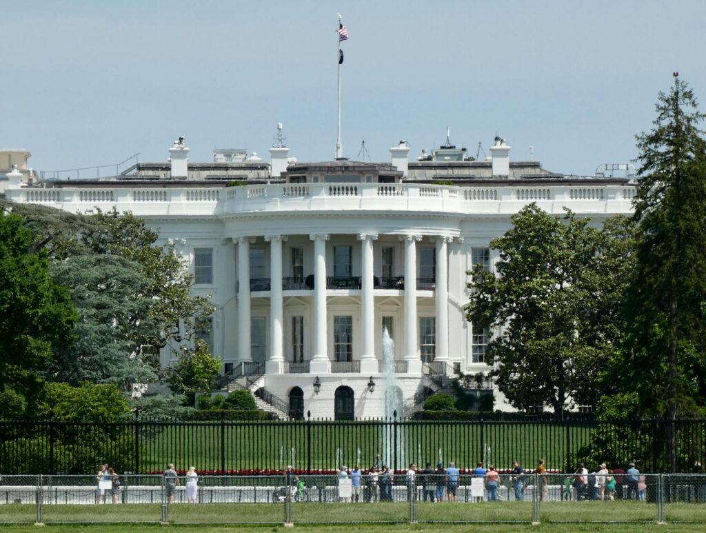 people standing outside the fence of the white house in washington